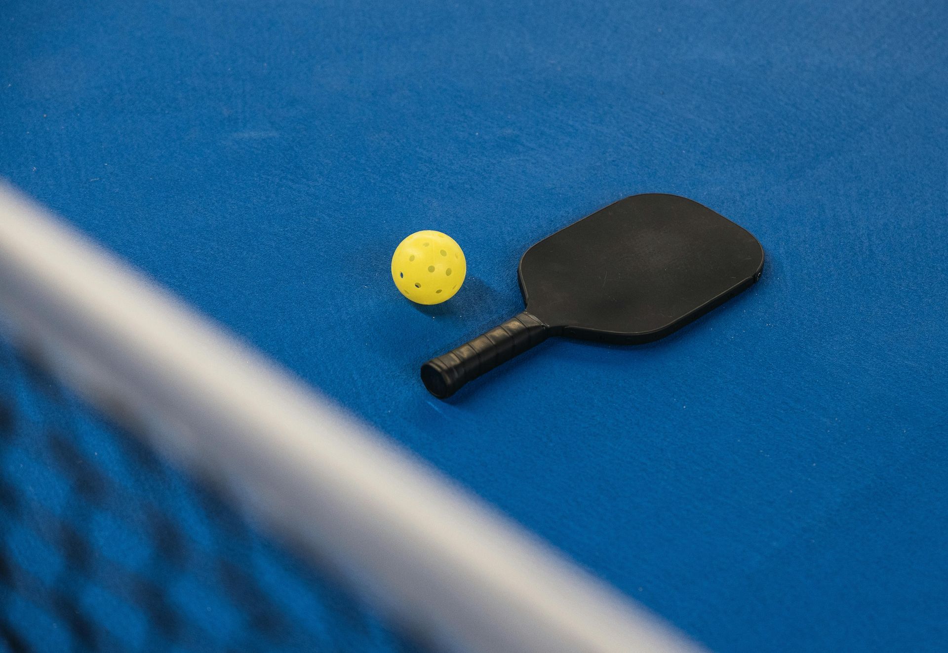 A paddle and a ball are on a blue table.