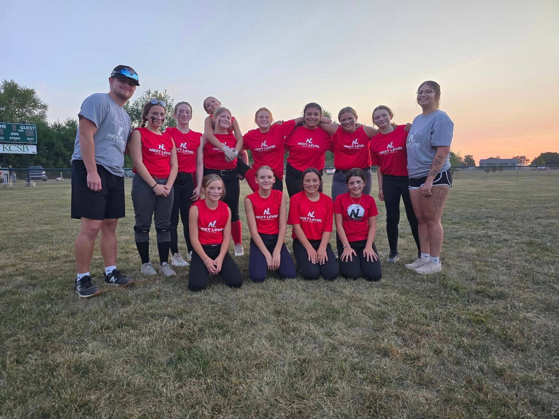 Volleyball player spikes the ball mid-air. Red and black uniforms on a red court.