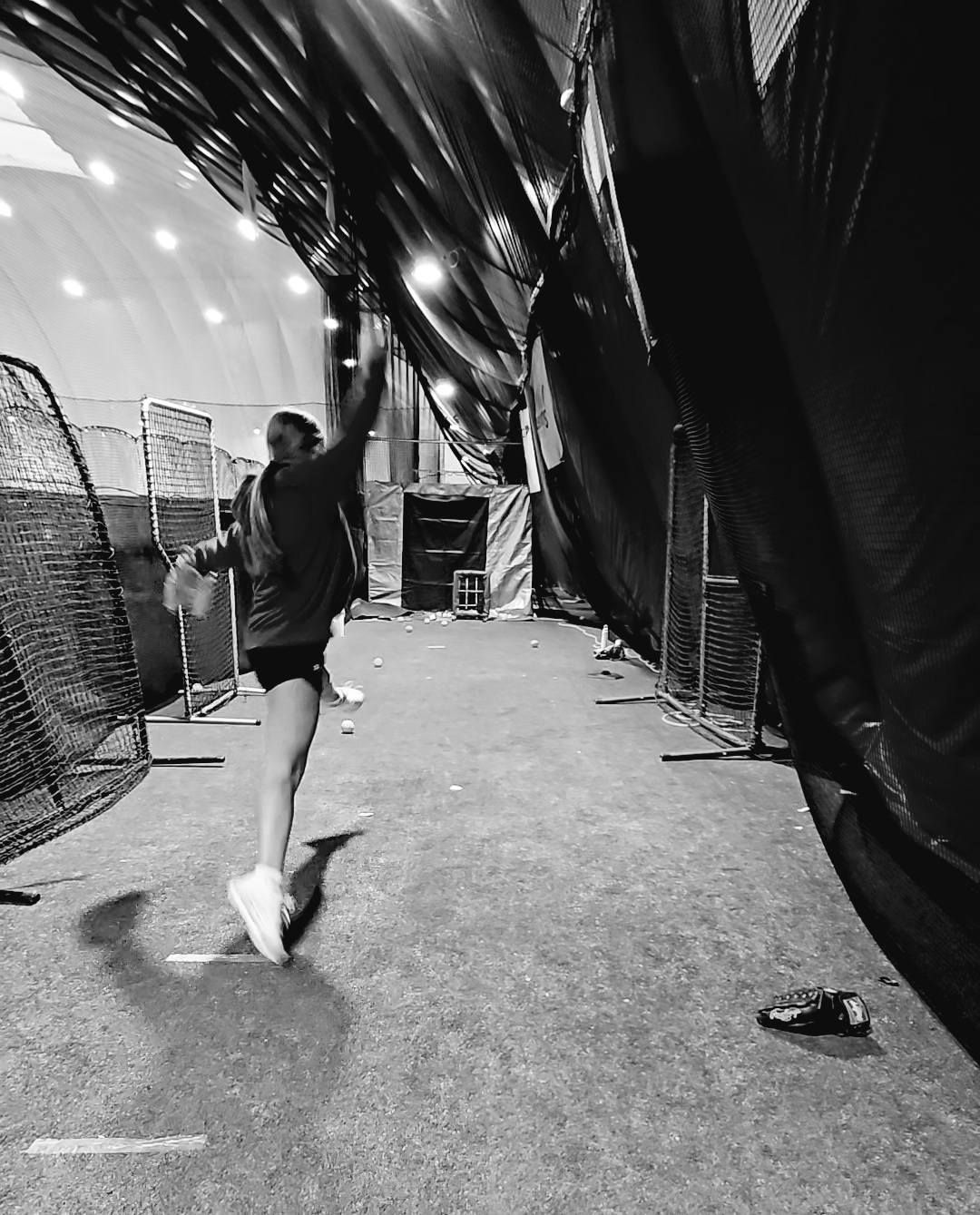 Volleyball player spikes the ball mid-air. Red and black uniforms on a red court.