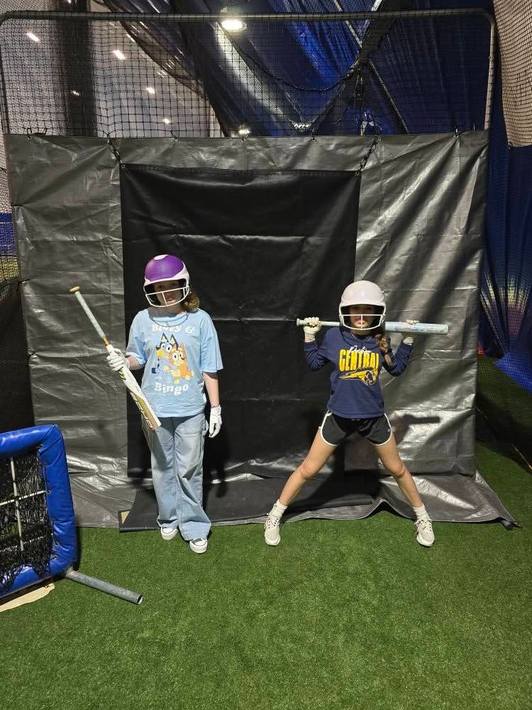 Volleyball player spikes the ball mid-air. Red and black uniforms on a red court.