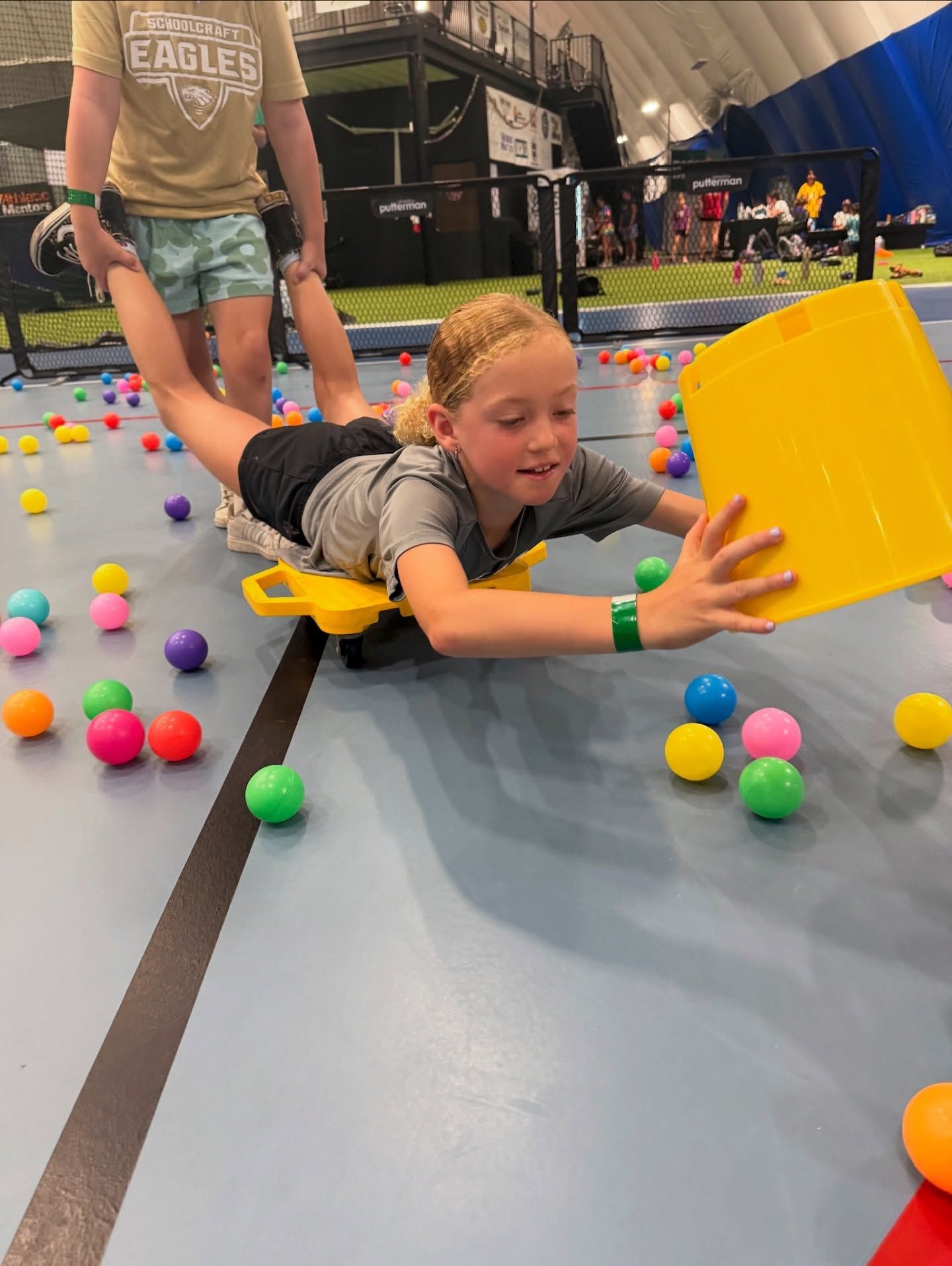 Aerial view of a baseball field, playground, and parking lot. The field is green, with red and brown elements.