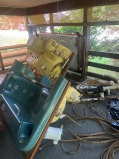 Deconstructed hot tub, teal and yellow sections, surrounded by debris, in a wooden gazebo.