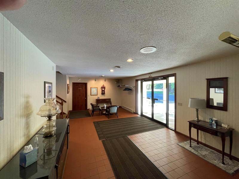 Interior entryway with wood-paneled walls, red tile floor, and double doors leading outside.