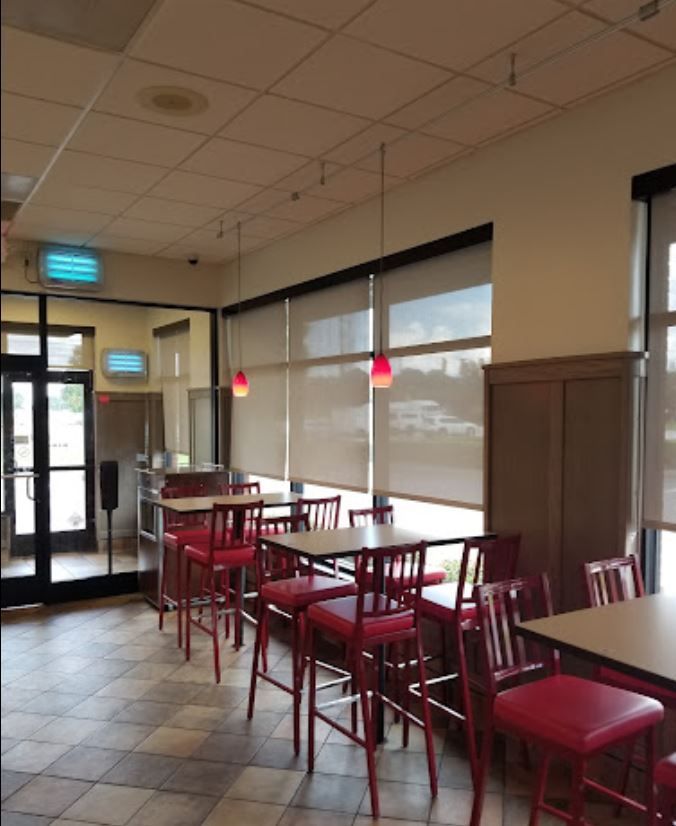 A restaurant with tables and chairs and blinds on the windows