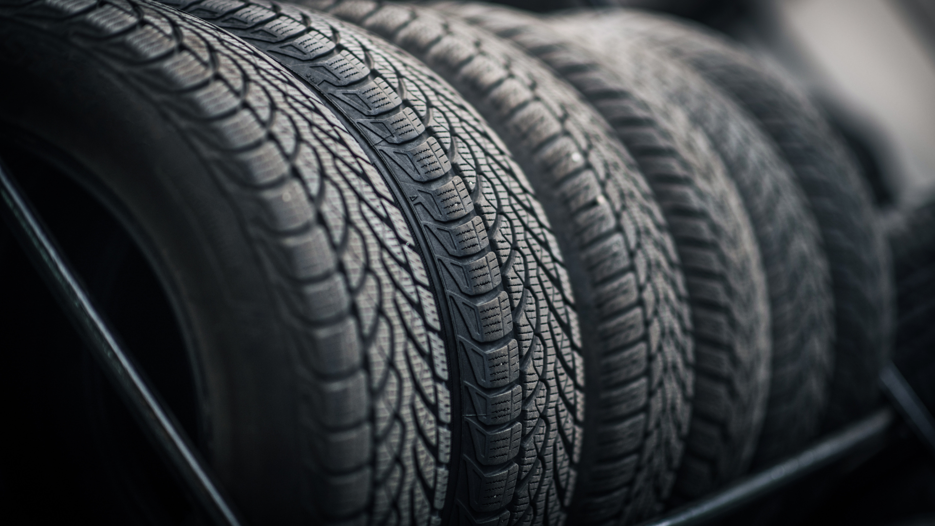 Tires stacked in a row, featuring a textured tread pattern.