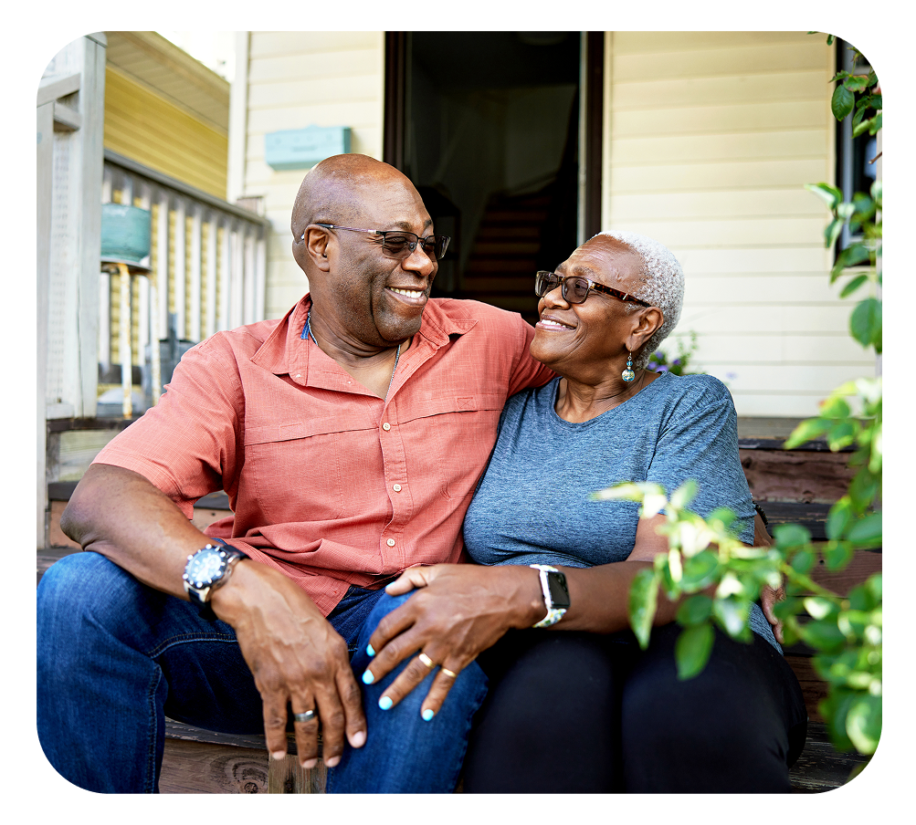 Couple smiling, sitting close together on porch steps, embracing.