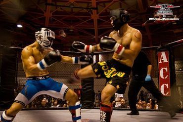 Two men are boxing in a ring with a sign that says acc on it.