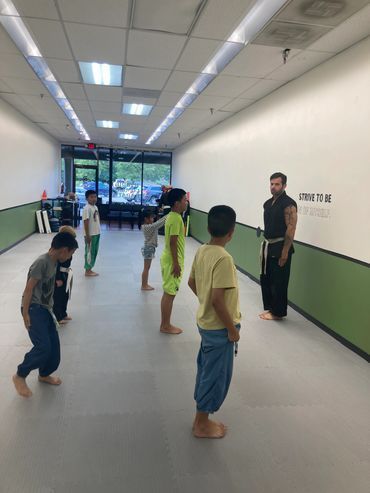 A group of young boys are practicing martial arts in a gym.