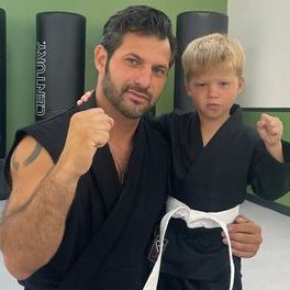 A man and a boy are posing for a picture in a gym.