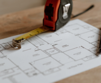A tape measure is sitting on top of a house plan.