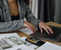 A woman is sitting at a table using a laptop computer.