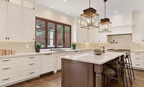 A kitchen with white cabinets and a large island in the middle.