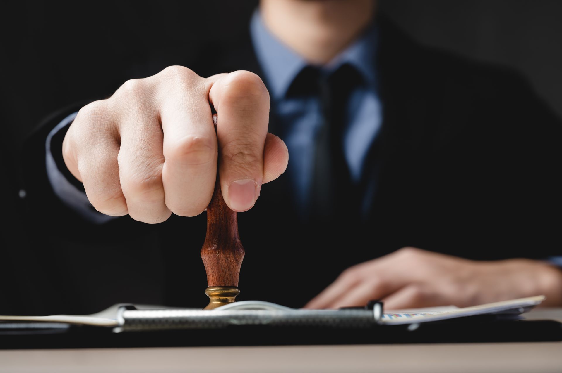 A man in a suit and tie is stamping a document with his finger.