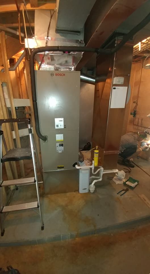 A man is working on a heating system in a basement.