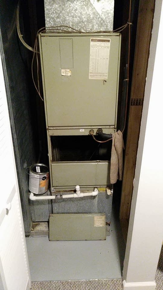 An air conditioner is sitting in a closet next to a wall.