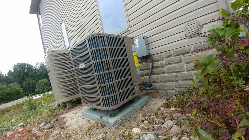 A large air conditioner is sitting on the side of a house.