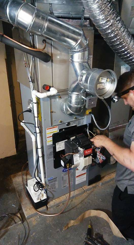 A man is working on a heating system in a basement.