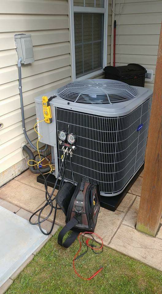 An air conditioner is sitting on the side of a house next to a window.