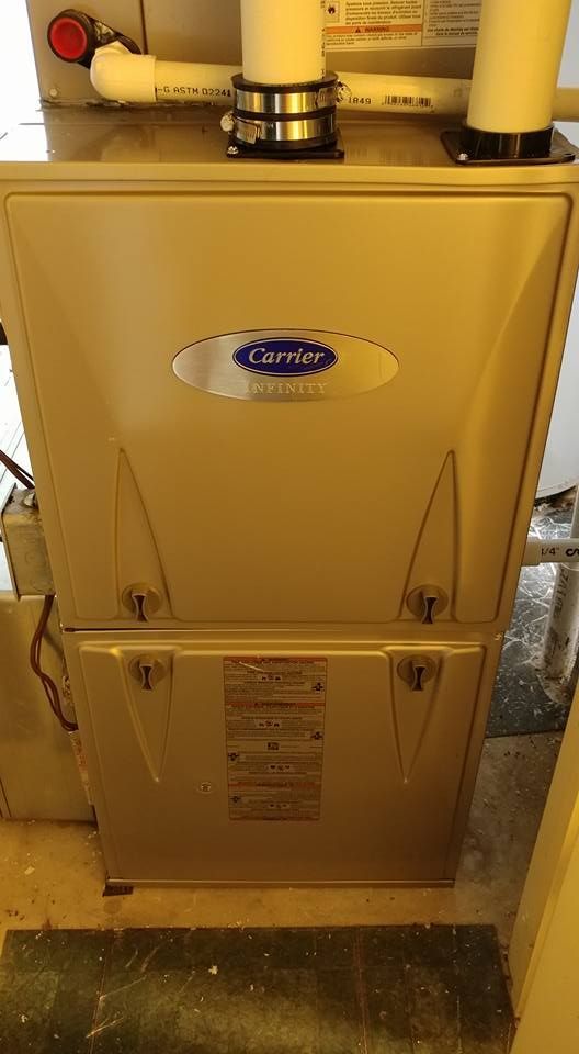 A carrier air conditioner is sitting on the floor in a room.
