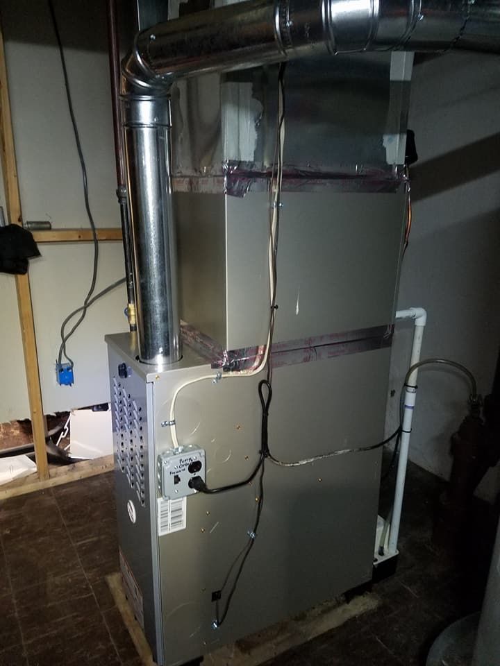 A furnace is sitting in a basement next to a wall.