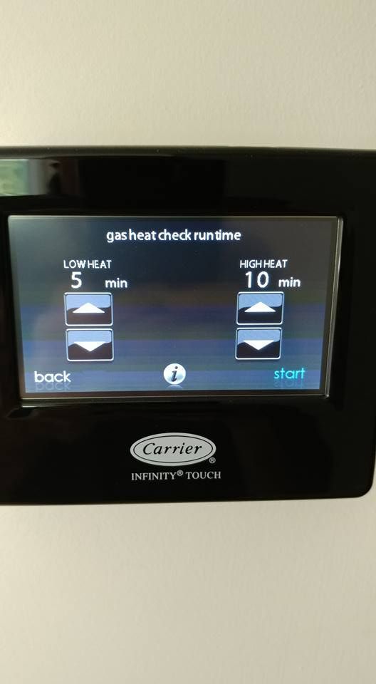 A thermostat with a screen on it is hanging on a wall.