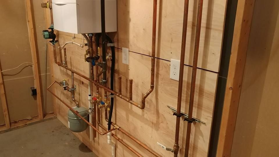 A room with a boiler and pipes on the wall.