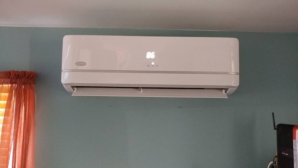 A white air conditioner is hanging on a blue wall in a room.