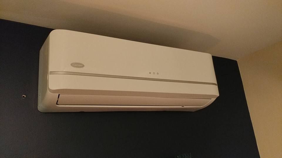 A white air conditioner is hanging from the ceiling in a room.
