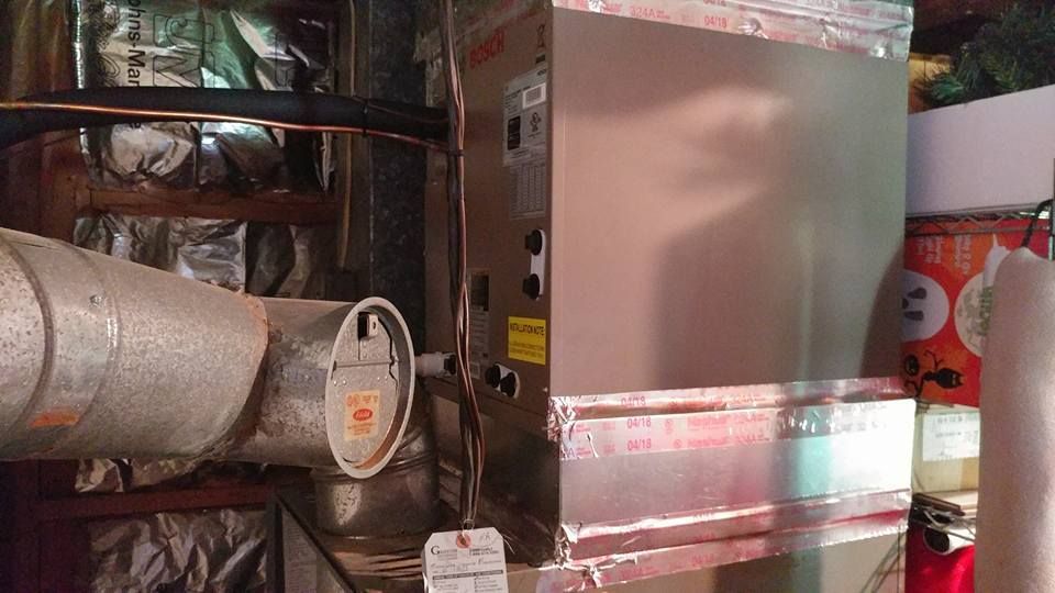 A metal box is sitting in a room next to a pipe.