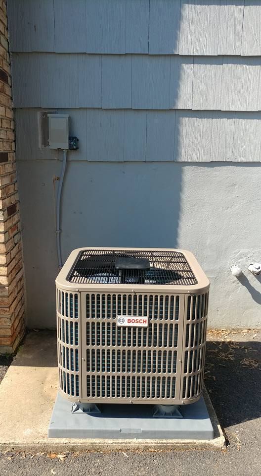A large air conditioner is sitting outside of a building.
