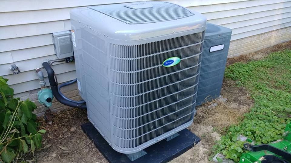 A large air conditioner is sitting outside of a house.