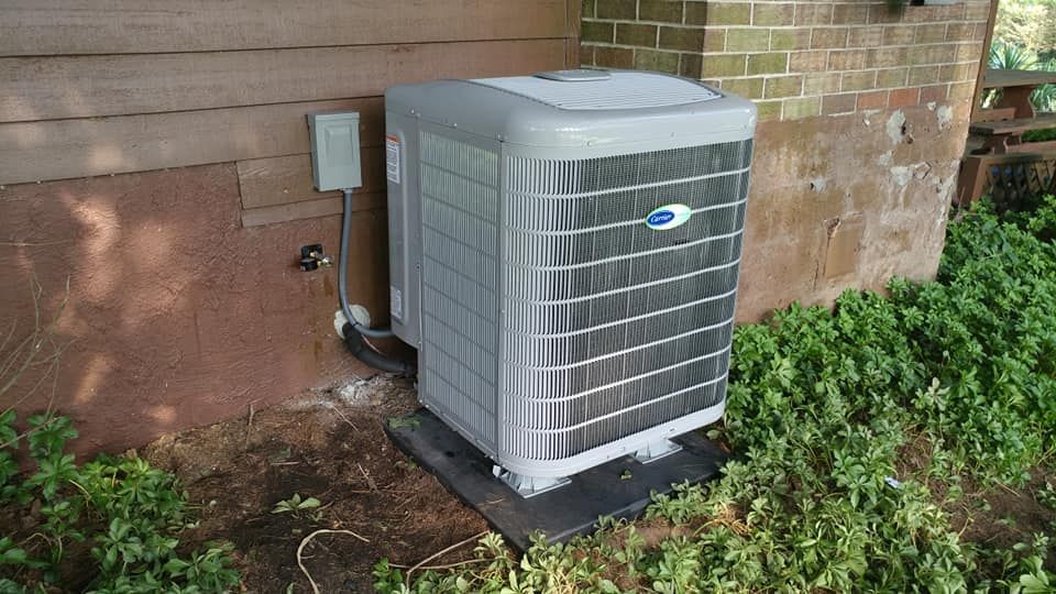 An air conditioner is sitting on the side of a brick building.