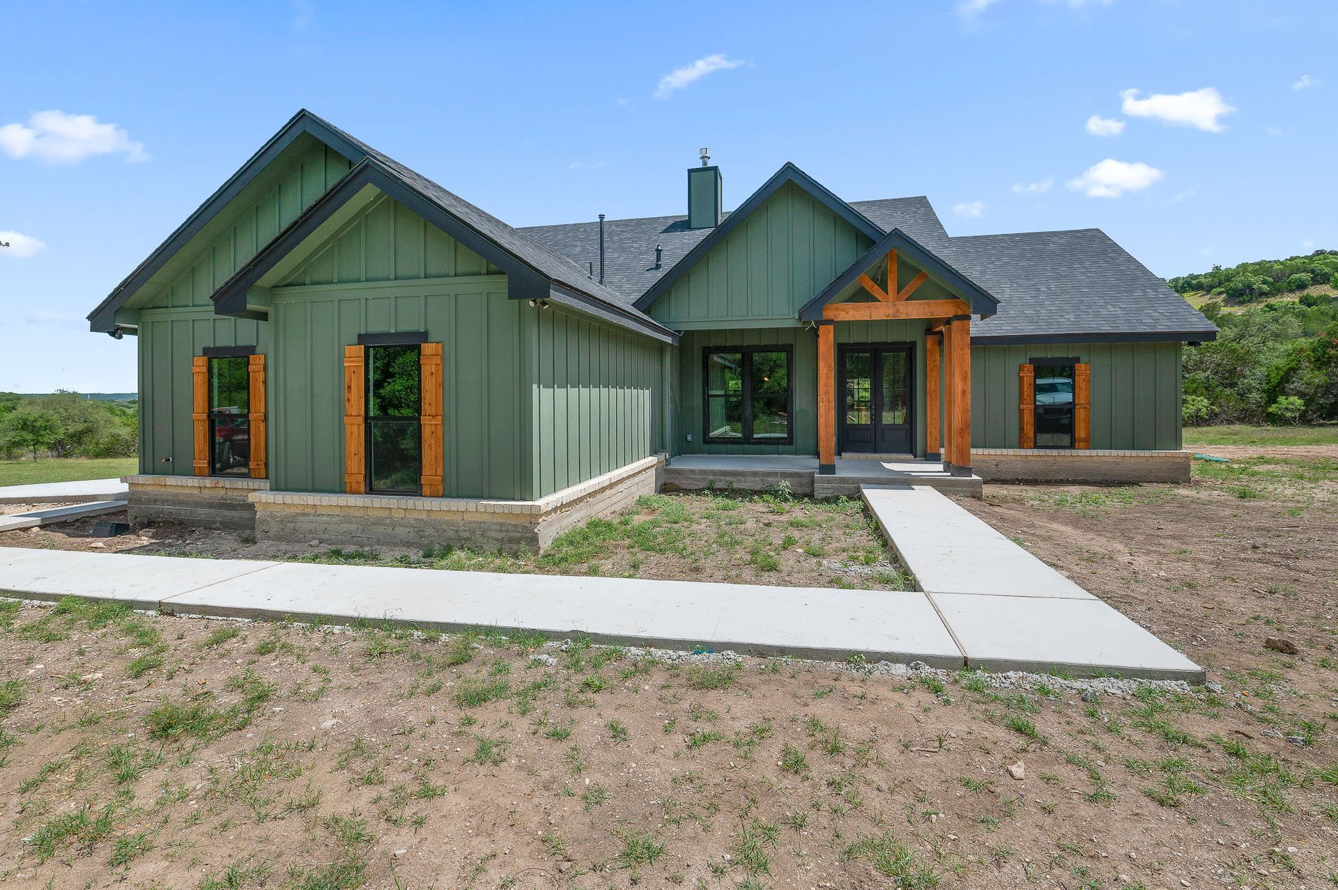 A green house with a concrete walkway leading to it.