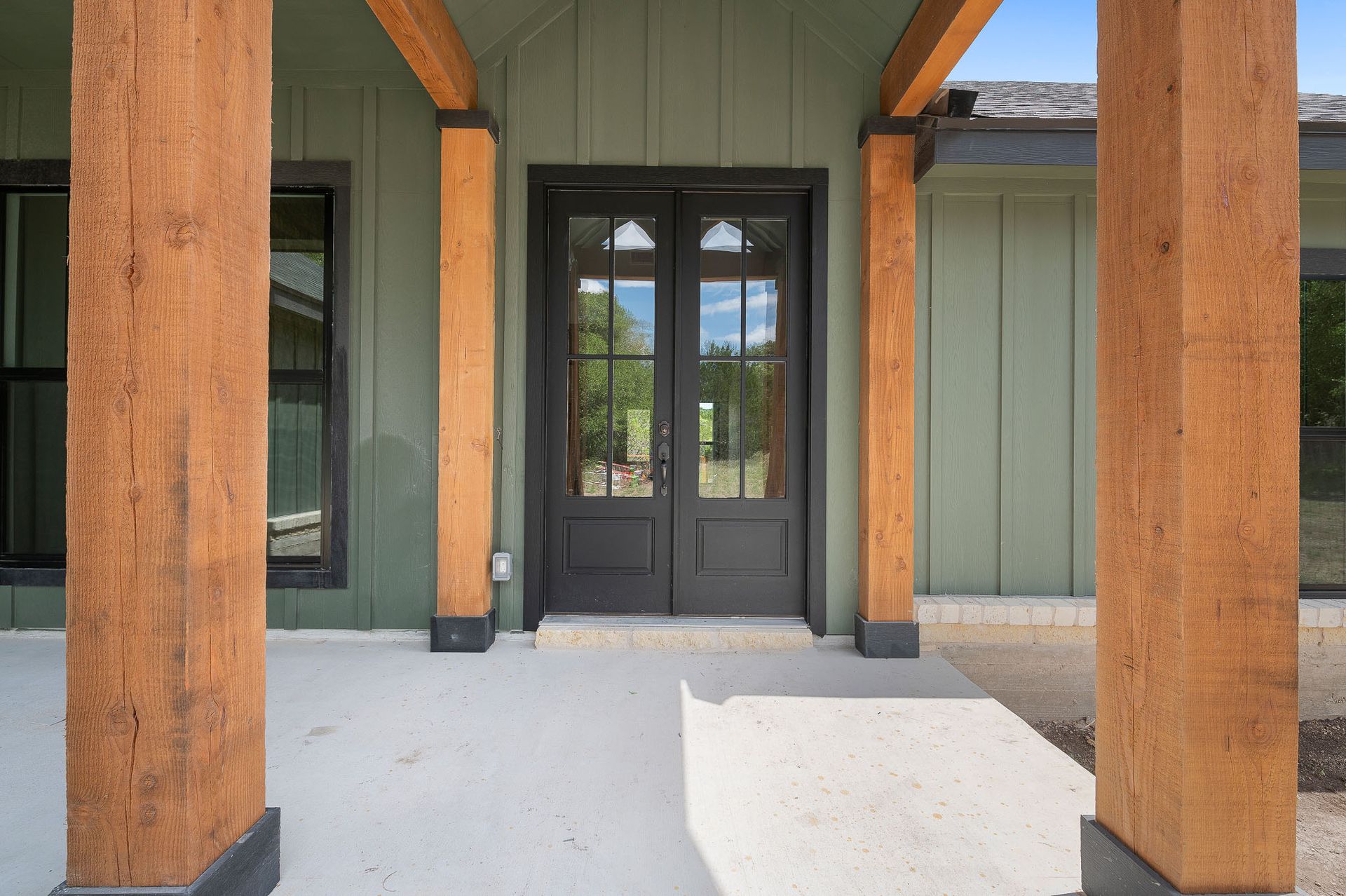 The front door of a house with a porch and wooden pillars.