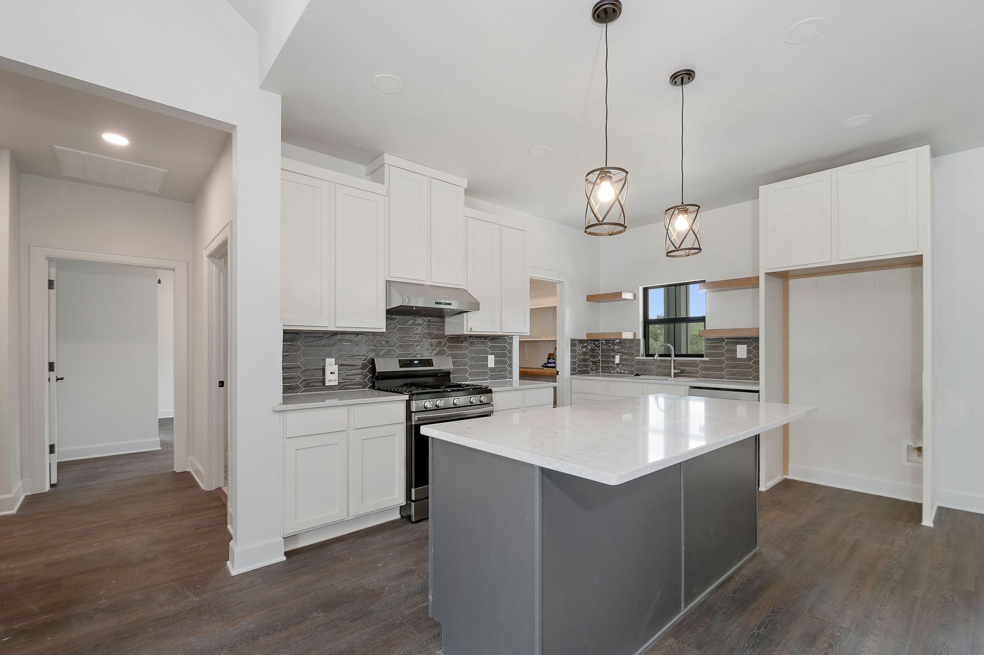A kitchen with white cabinets , stainless steel appliances , and a large island.