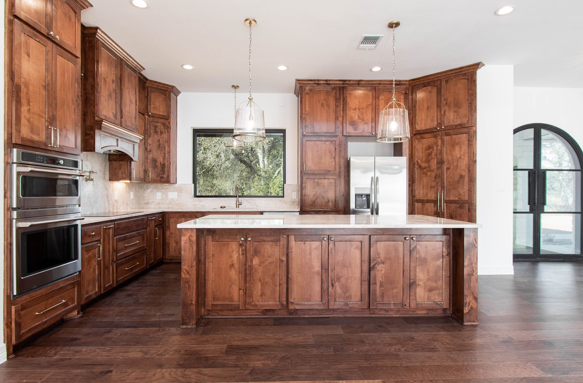 A kitchen with wooden cabinets , stainless steel appliances , and a large island.