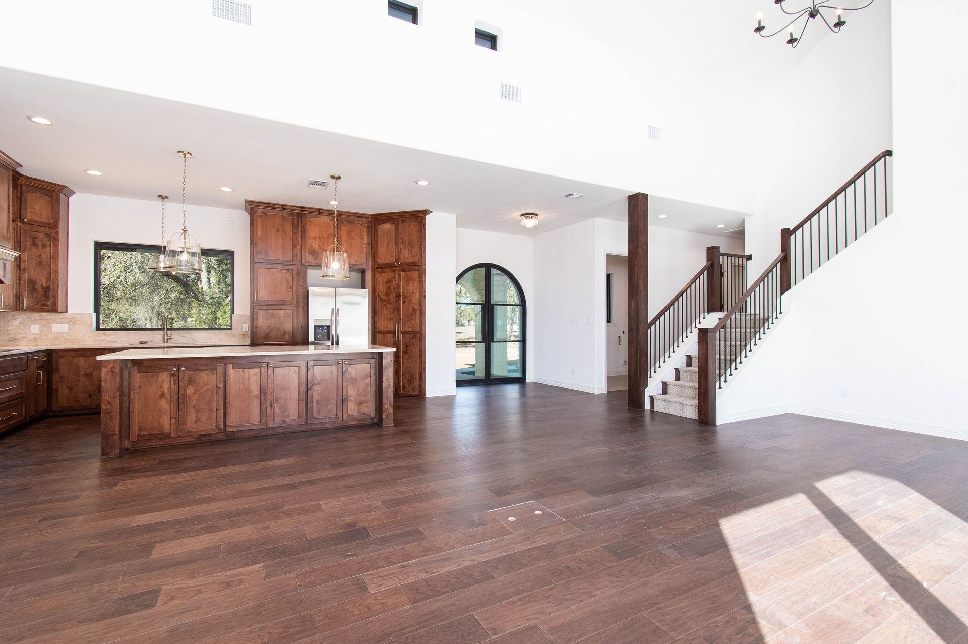 An empty kitchen with a large island and stairs leading up to the second floor.