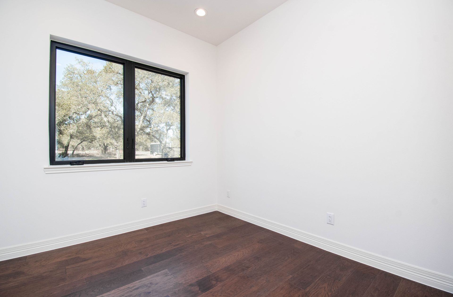 An empty room with hardwood floors and a large window.