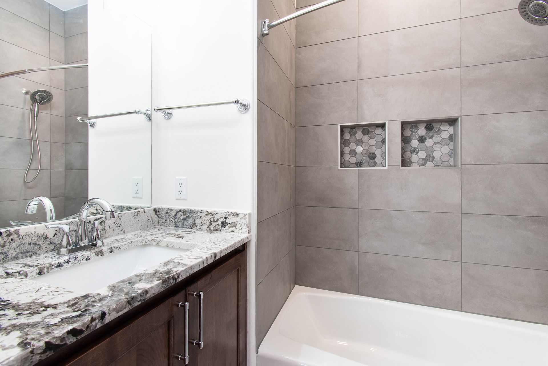 A bathroom with a sink , tub , shower and mirror.