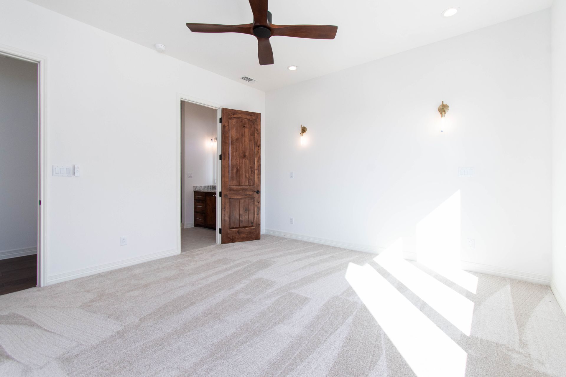 An empty bedroom with a ceiling fan and a wooden door