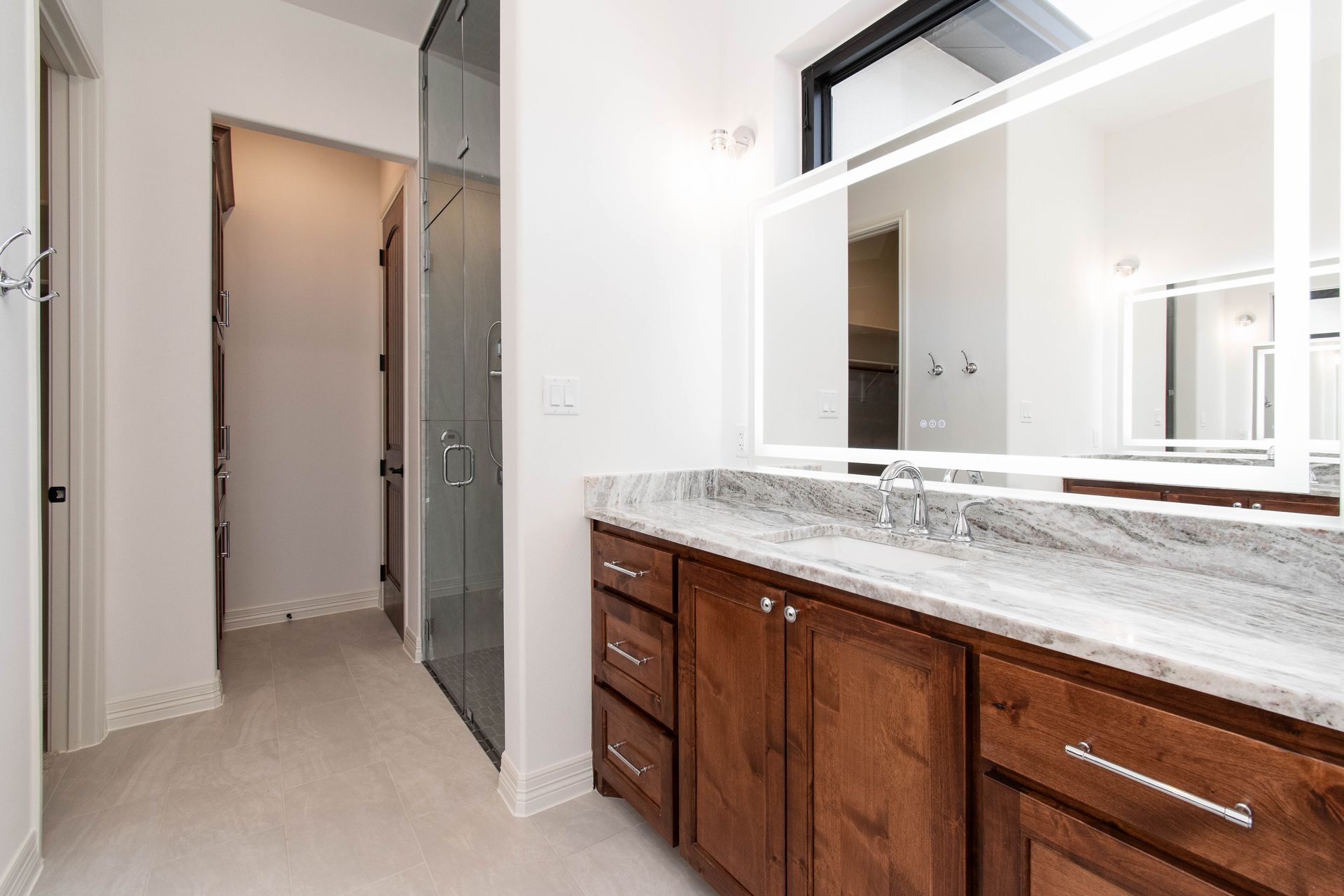 A bathroom with two sinks , a mirror and a walk in shower.