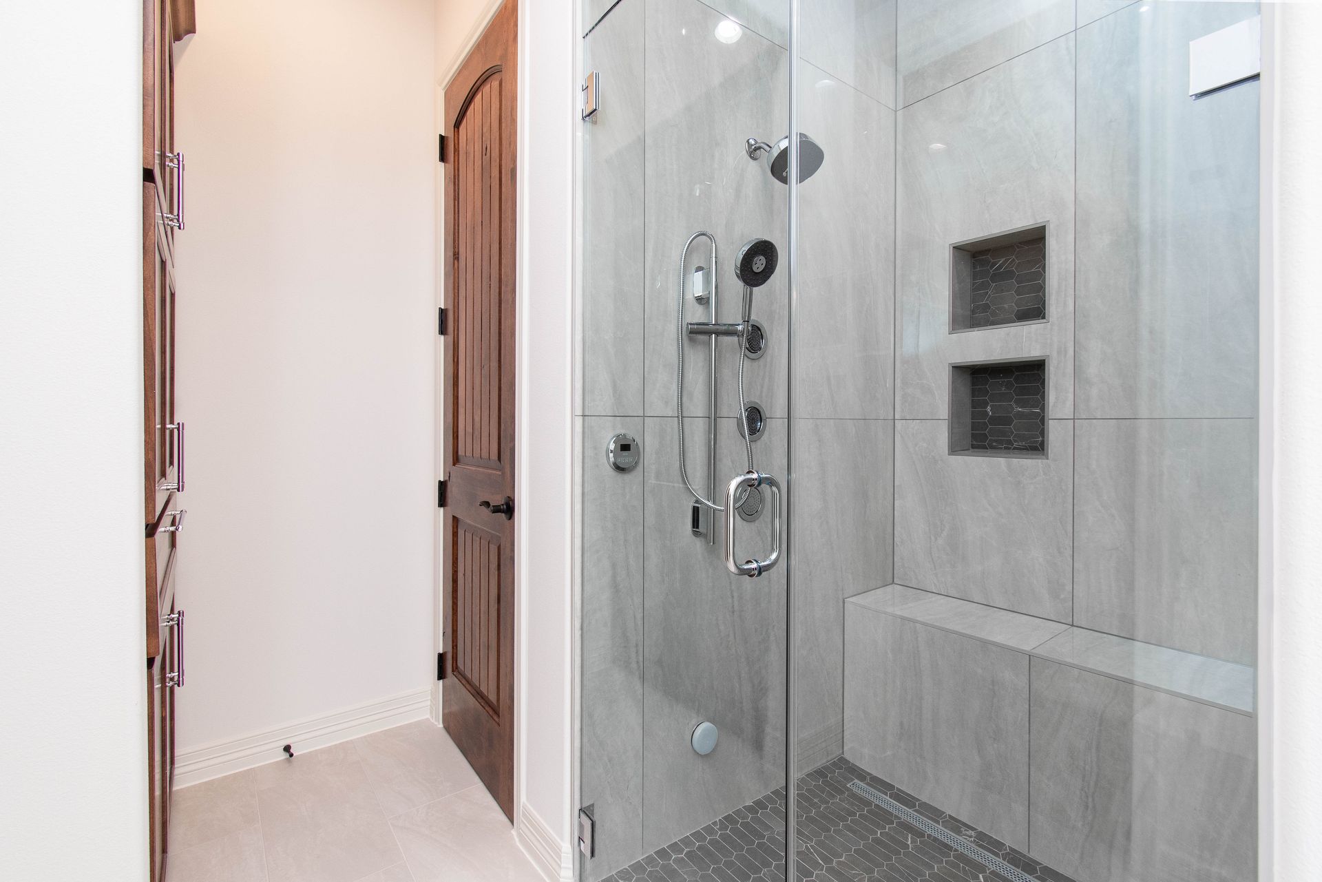 A bathroom with a walk in shower with a glass door.