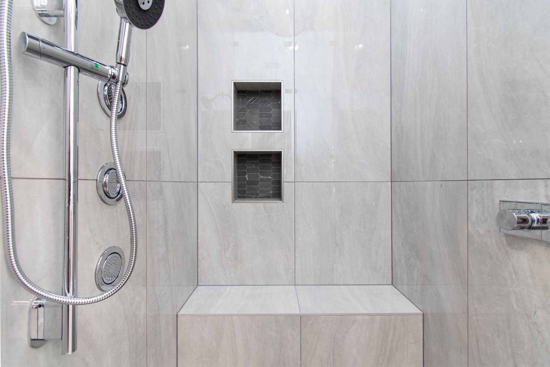 A bathroom with a shower head and a bench.