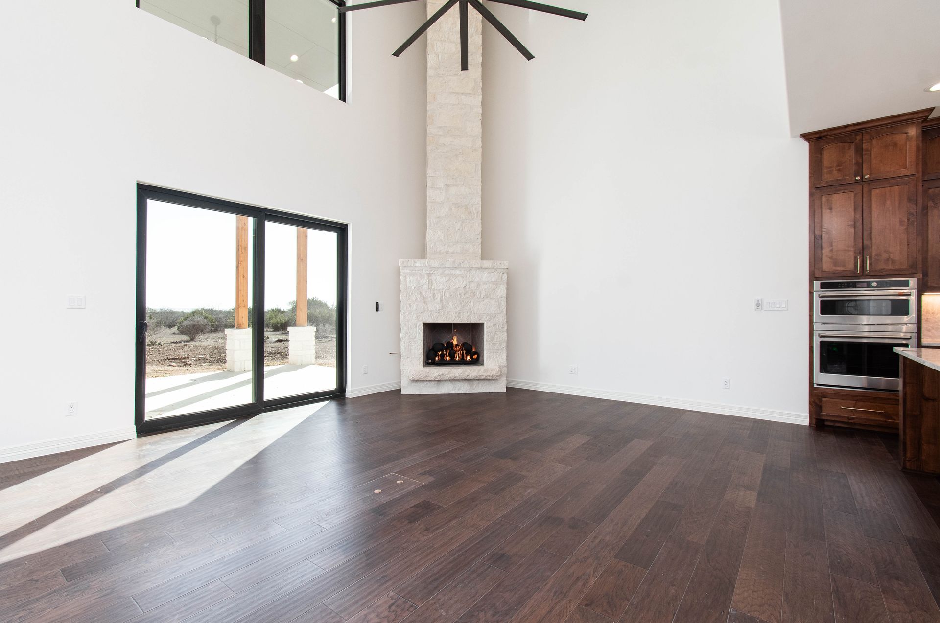An empty living room with a fireplace and sliding glass doors.