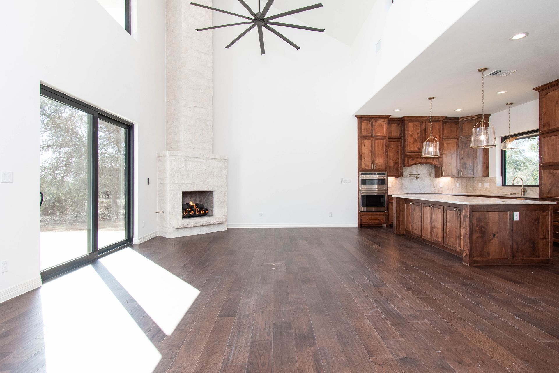 An empty living room with a fireplace and a ceiling fan
