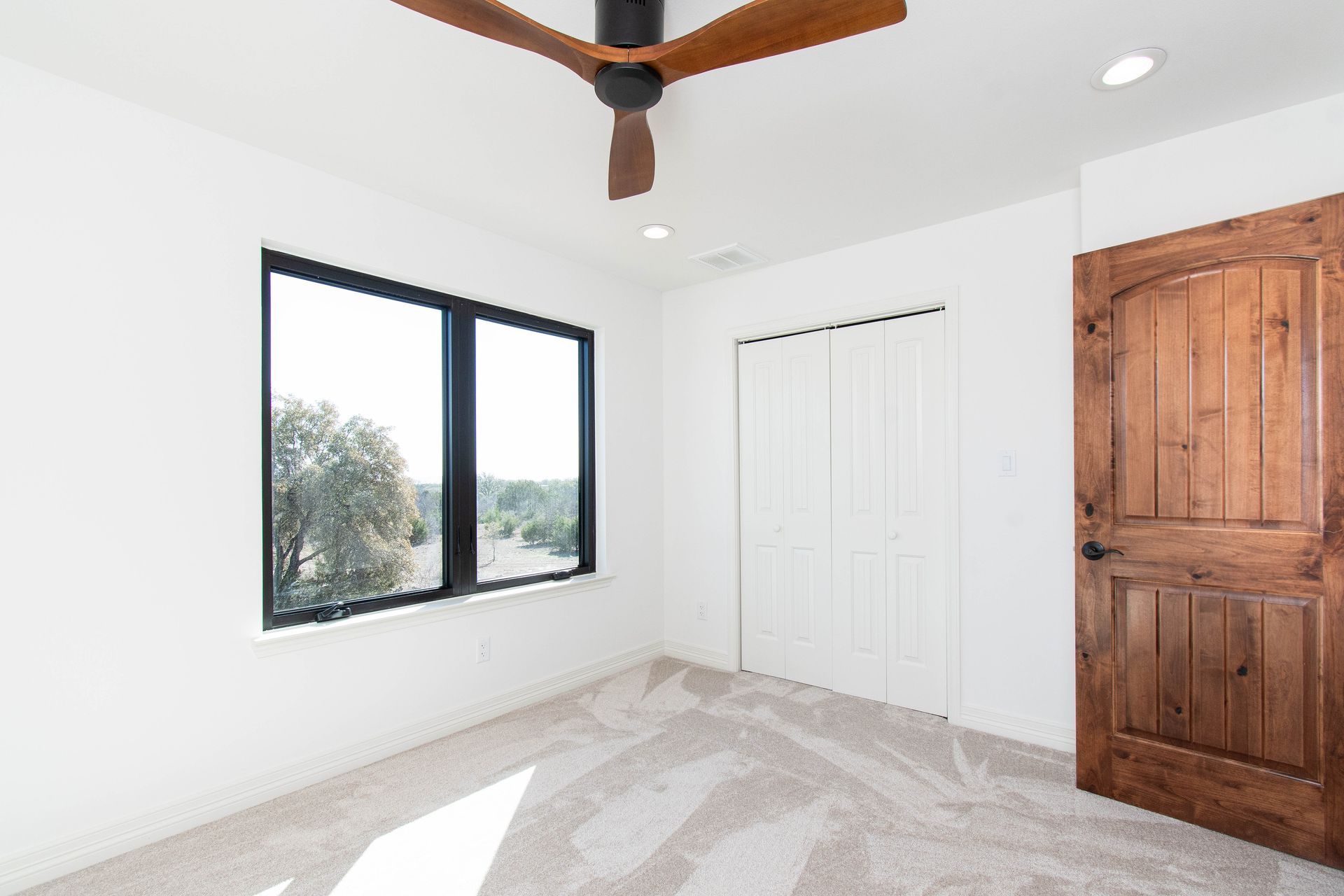 An empty bedroom with a ceiling fan and two windows.