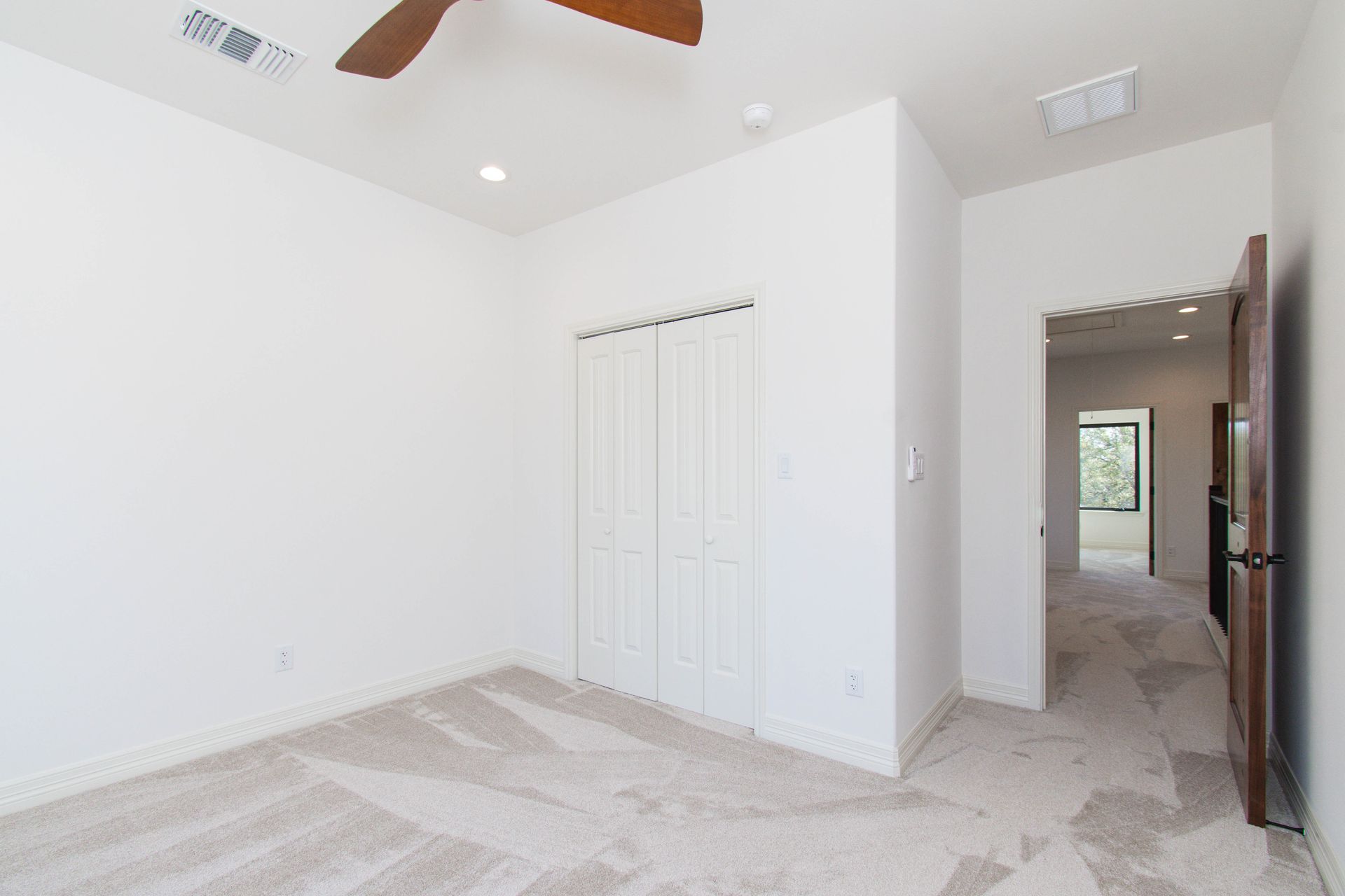 A bedroom with a ceiling fan and a closet.