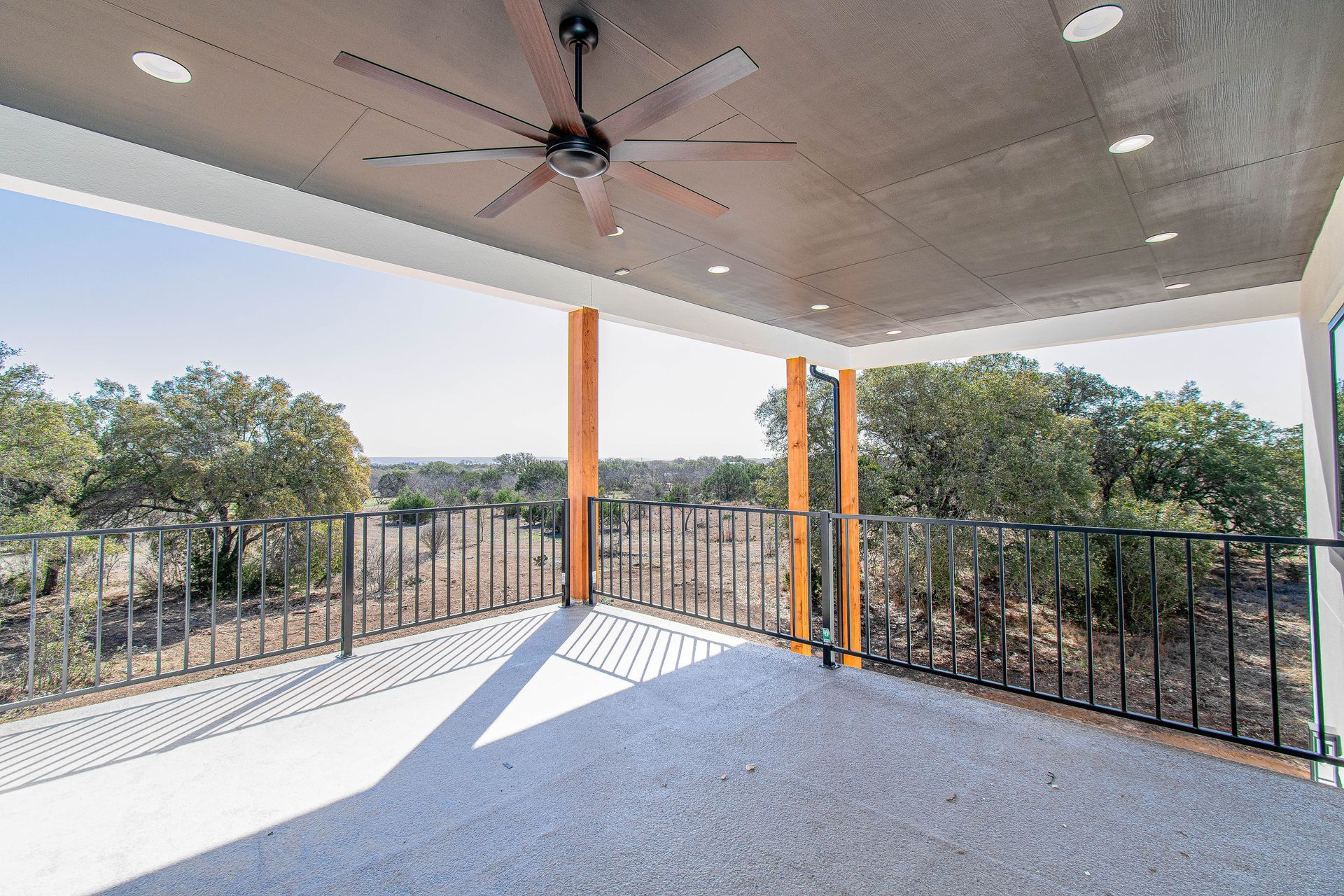 A balcony with a ceiling fan and a view of trees.