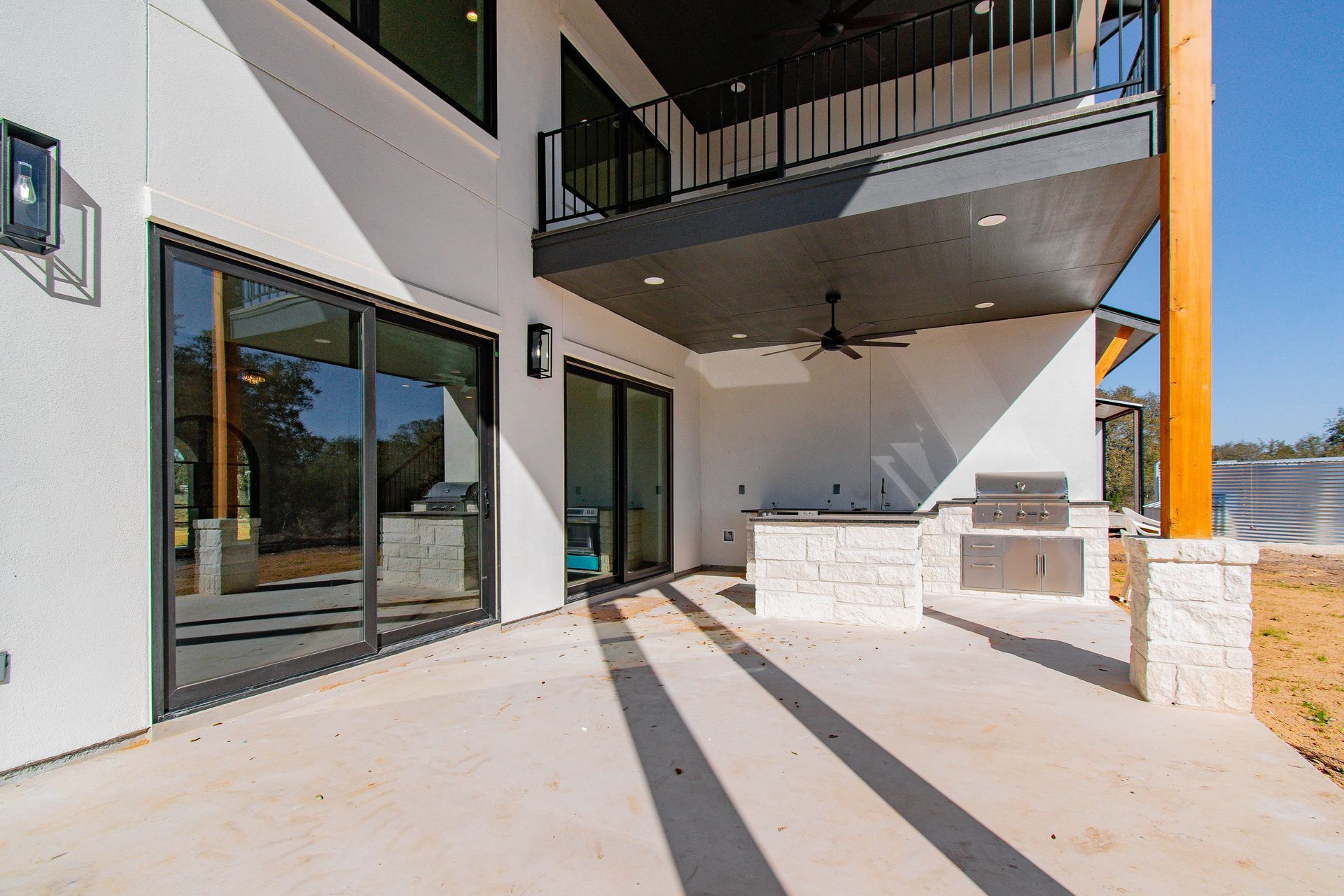A large white house with a patio with sliding glass doors and a grill.