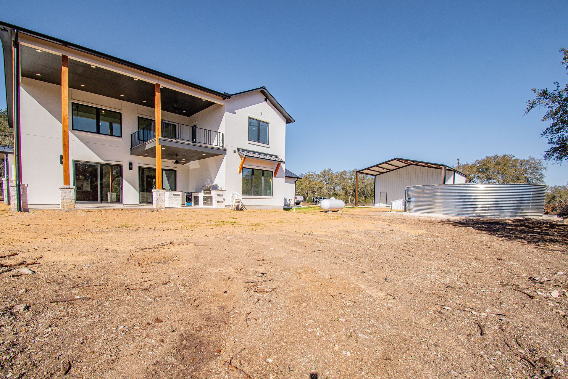 A large white house is sitting on top of a dirt field.